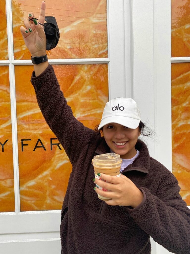 Student with iced coffee pointing upwards