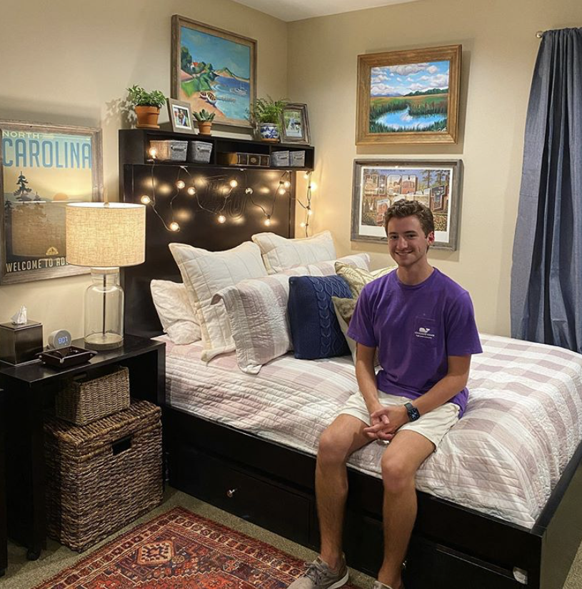 A student sitting in his dorm decorated with string lights and pictures