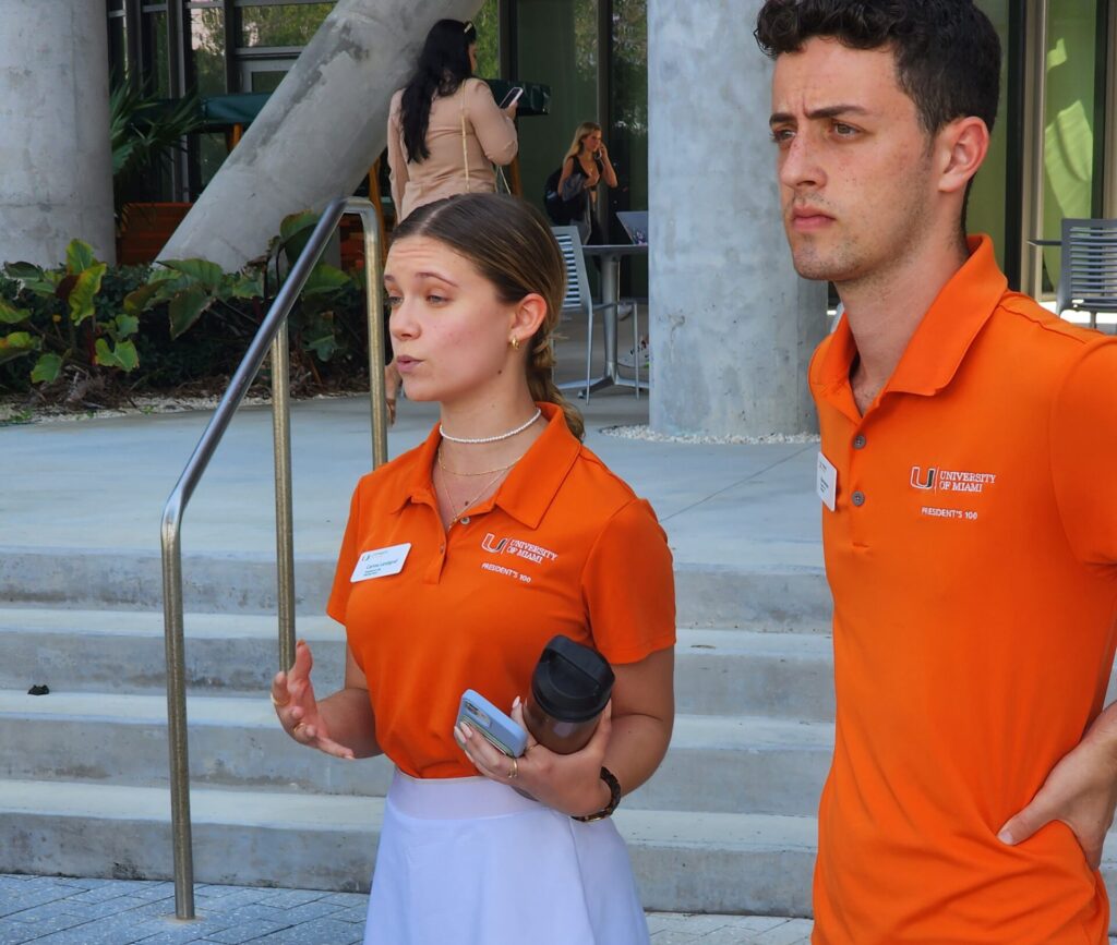 Males and female Miami student tour guides dressed in orange U of Miami polos.