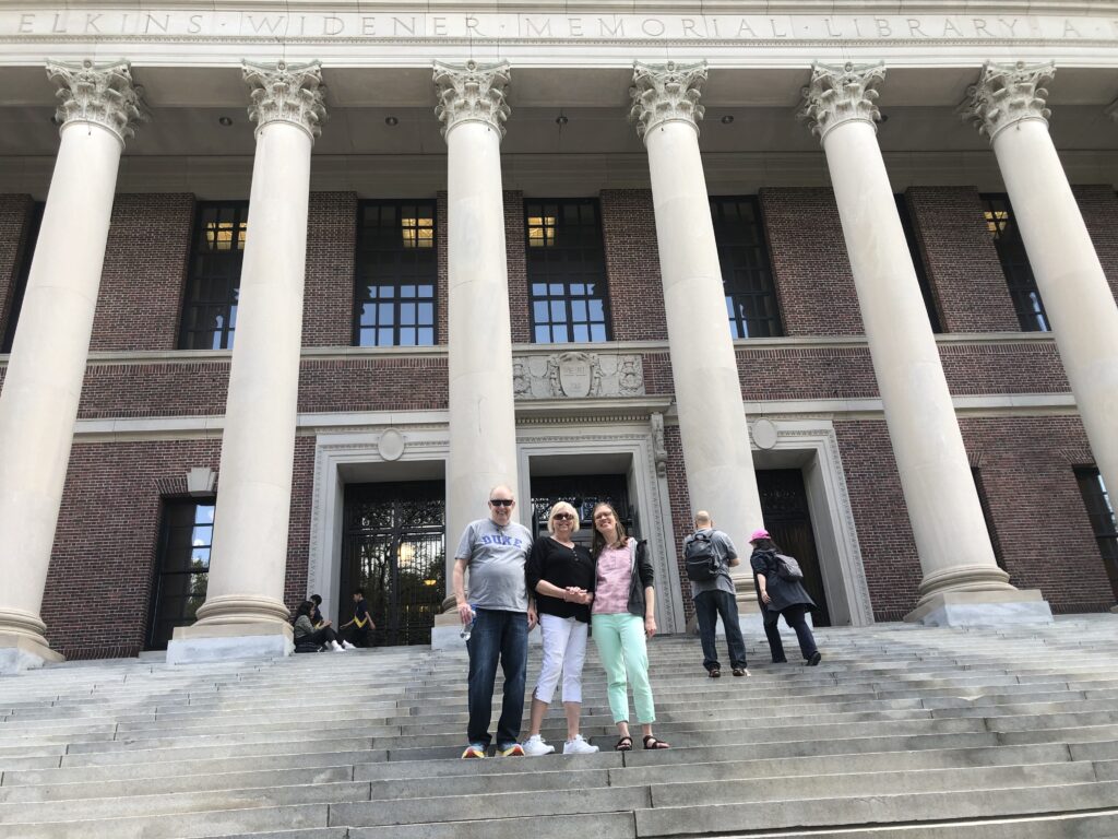 Author and two others pictured on steps in front of massive pillars of Widener Library