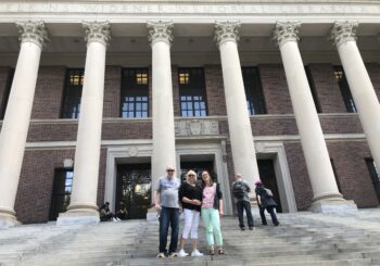 Author and two others pictured on steps in front of massive pillars of Widener Library