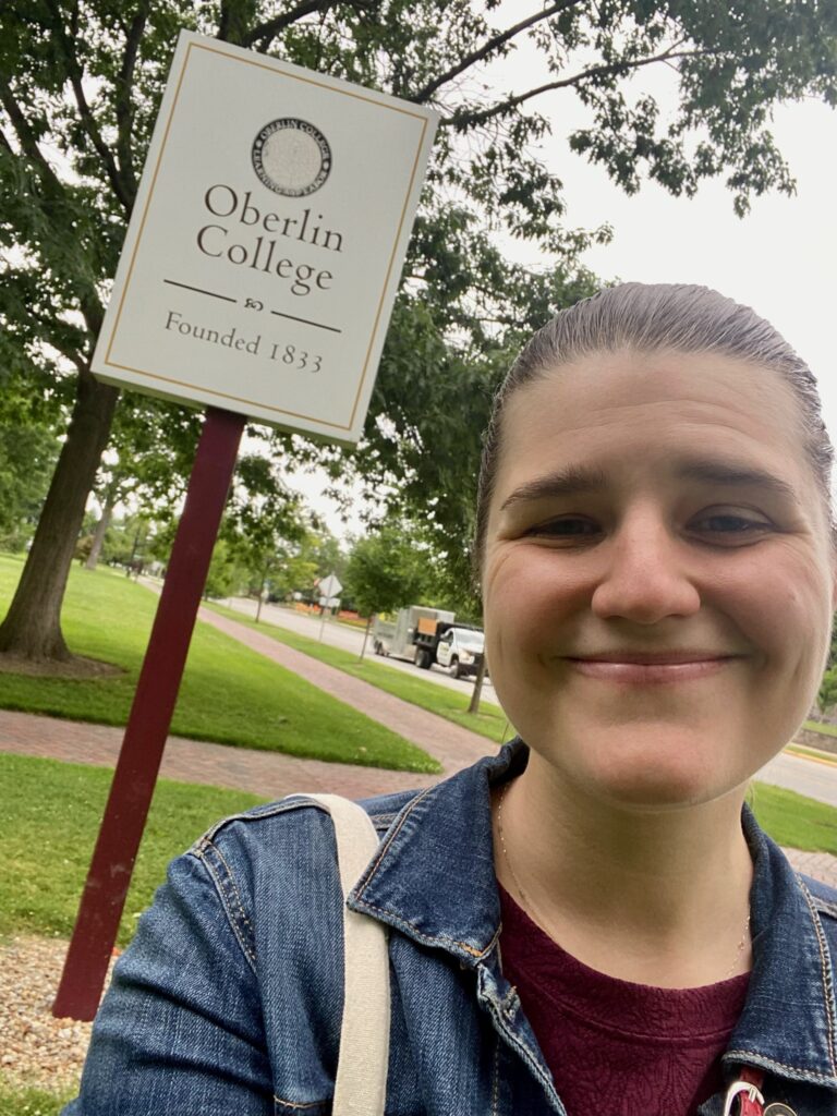 Author (Aleece) smiling in front of Oberlin College founded in 1833 sign.